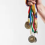 mature-man-holding-gold-medals-against-white-backg-2023-11-27-05-15-53-utc